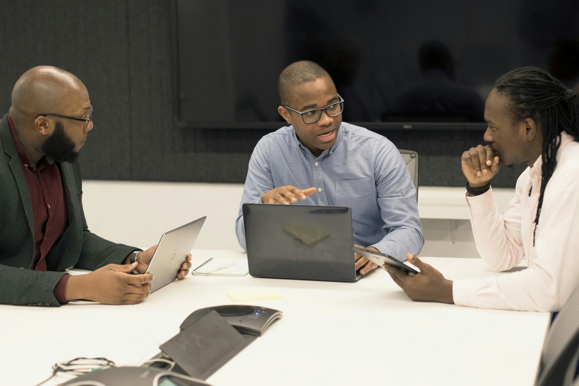 Black professionals in a project meeting, collaborating with laptops in a modern office